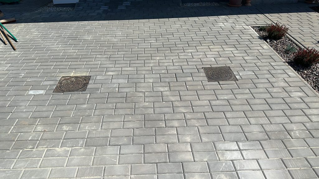 Plocha zámkové dlažby typu Holland s integrovanými kanalizačními vpustmi, použitá jako příklad moderních druhů zámkové dlažby pro vjezdy a parkovací plochy.
