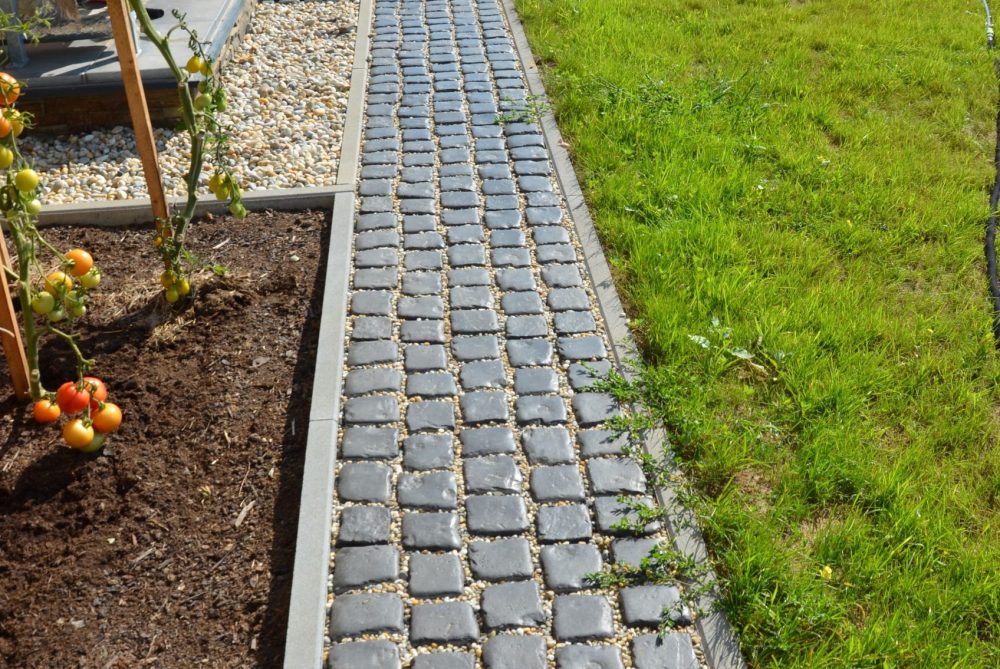 Zahradní obrubník s položenou zámkovou dlažbou kolem rodinného domu – estetické a funkční oddělení záhonu a trávníku